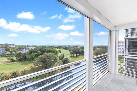 Panoramic view from a balcony overlooking a green area and distant buildings.