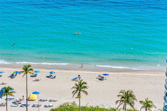 View of a sandy beach with umbrellas and ocean waves.