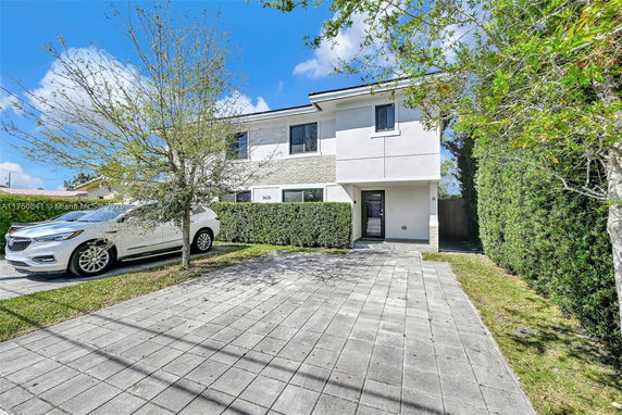 Front view of a two-story house with a paved driveway and a parked car.
