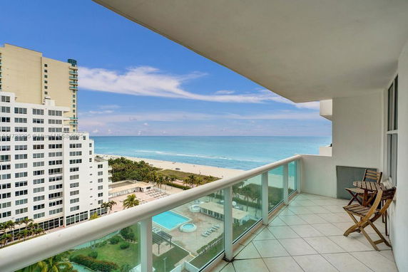 View from a balcony overlooking an ocean and nearby buildings.