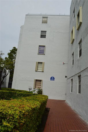 Side view of a multi-story building with white exterior walls and several windows.