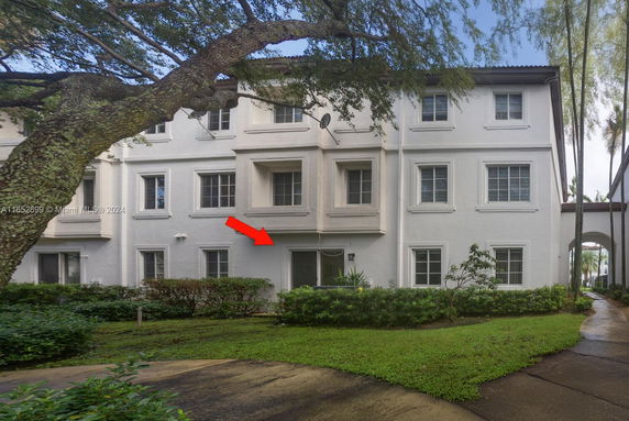 Front view of a multi-story building with multiple windows and a small lawn area.