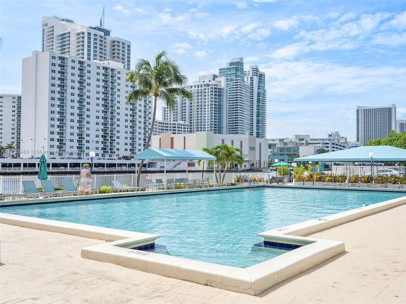 View of a large swimming pool with high-rise residential buildings in the background.