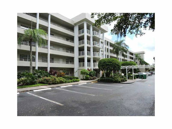 Front view of a multi-story apartment building with balconies and parking area.