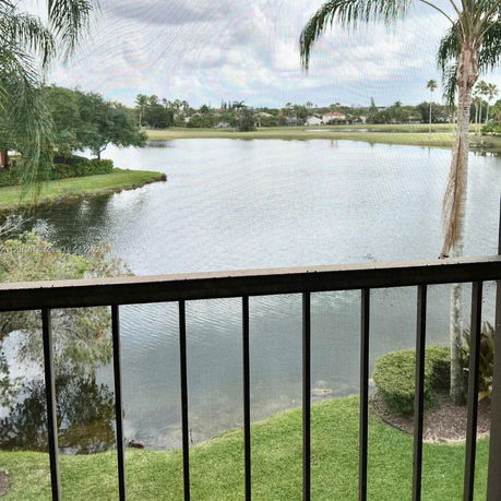 View from a balcony overlooking a lake with surrounding greenery and trees.