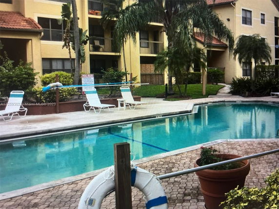 Outdoor swimming pool area with lounge chairs and surrounding apartment buildings.