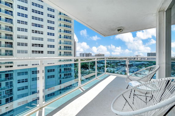 View from a balcony showcasing adjacent high-rise buildings and a cityscape.