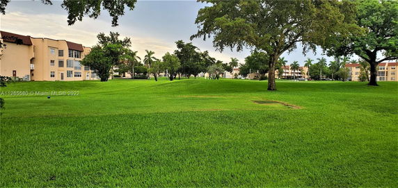 View of multiple residential buildings surrounded by grassy areas and trees.