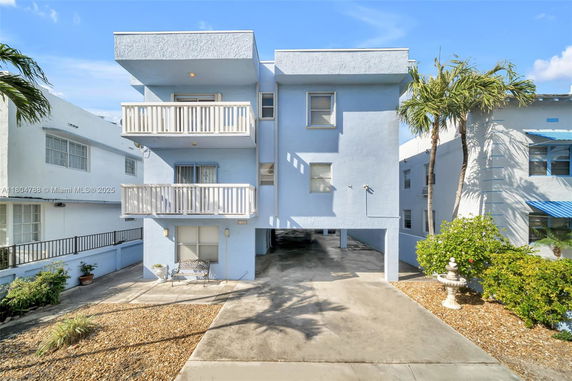 Front view of a three-story building with balconies and a carport.