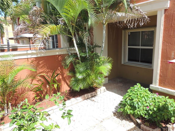 Side view of a building with a window, plants, and a small patio area.