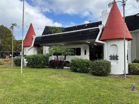 Front view of a building with unique red conical roof features and black and white exterior.