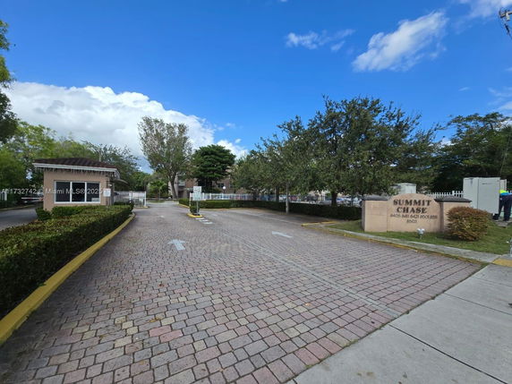 Entrance view of a residential complex with a gated entrance and sign reading 'Summit Chase.'