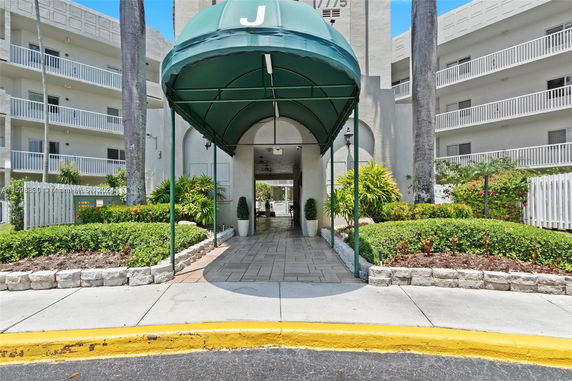 Front view of a multi-story building with balconies and a covered entrance.