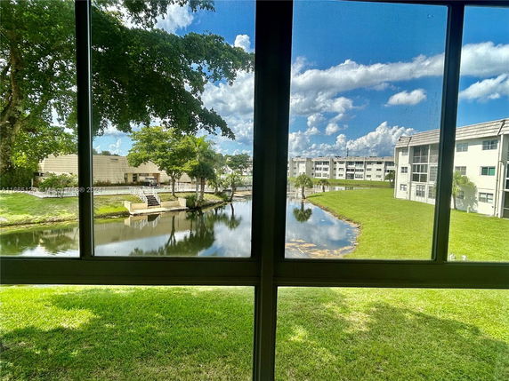 View of apartment buildings and a small pond seen through a window.