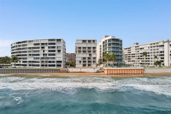Front view of beachfront multi-story buildings with glass balcony railings.