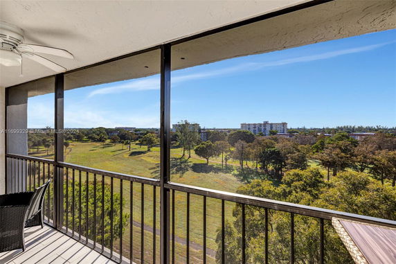 View from a balcony overlooking a grassy landscape with trees and distant buildings.