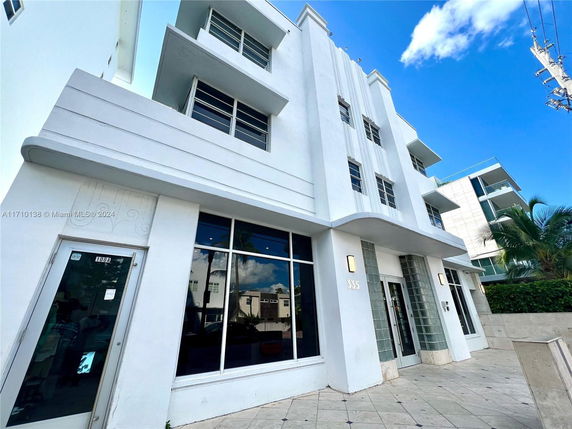 Front view of a multi-story modern building with large windows and a clean facade.