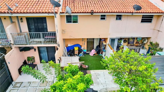 Overhead view showing a section of a two-story building with balconies, a patio area, and greenery.