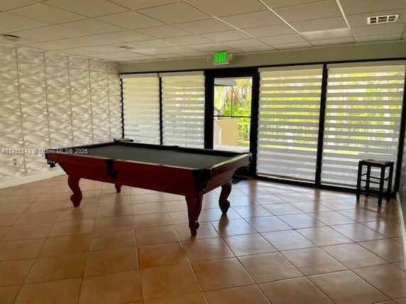 Room with a pool table and large windows.