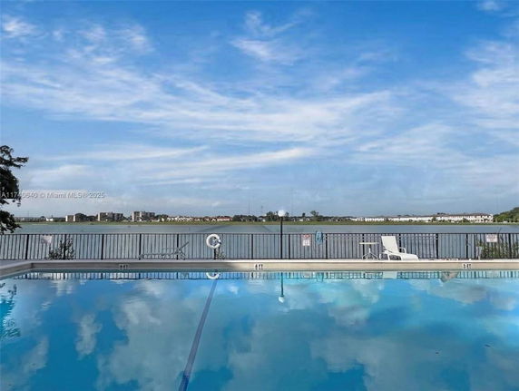 Outdoor swimming pool with a view of a lake and distant buildings.