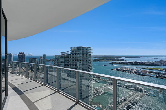 Panoramic view from a high-rise building balcony overlooking a city skyline and waterfront.