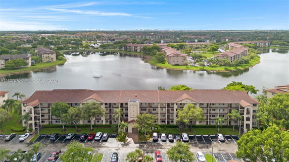 Aerial view of a residential complex near a large body of water and surrounded by greenery.