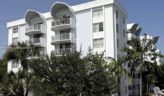 Front view of a multi-story white residential building with rounded balconies.