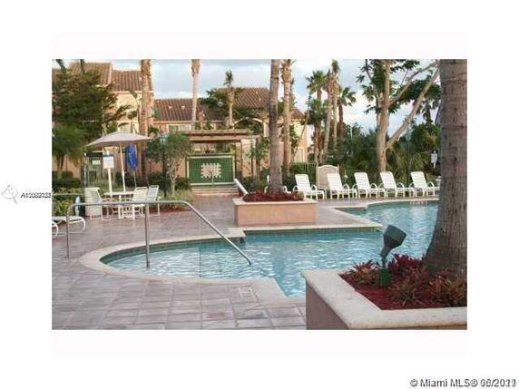 Outdoor swimming pool with lounge chairs and palm trees surrounding it.
