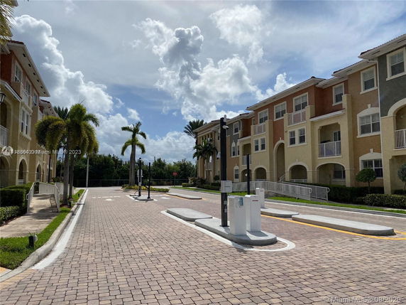Outdoor parking area near multi-story buildings with palm trees.