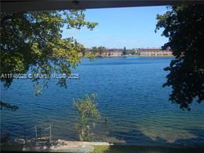 Wide view of a water body with trees on the sides and buildings in the distance.