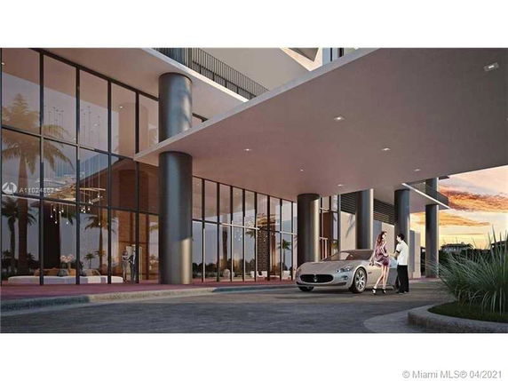 Entrance of a modern building with large glass windows and a covered driveway.