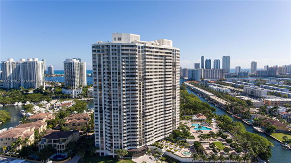 Tall luxury condominium building surrounded by other high-rise buildings and waterway views.