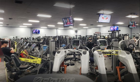 Interior view of a gym with various exercise machines and televisions.