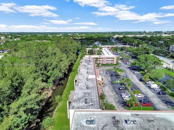 Aerial view of a building with surrounding greenery and parking lot.
