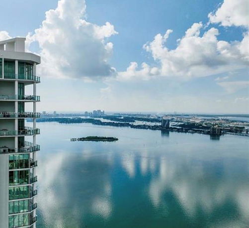 Panoramic view from a high-rise building overlooking a large body of water and distant land.