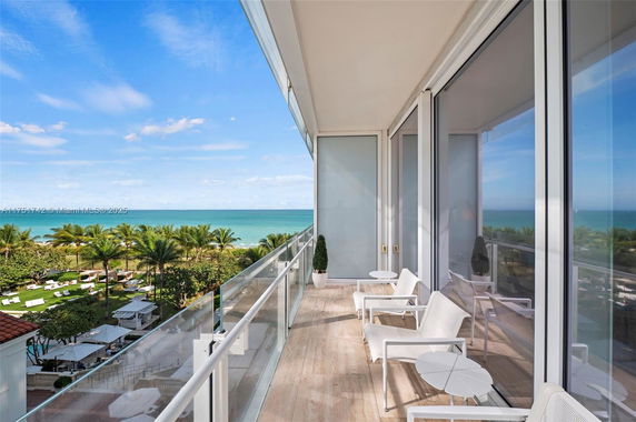 Panoramic view from a balcony overlooking the ocean and palm trees.