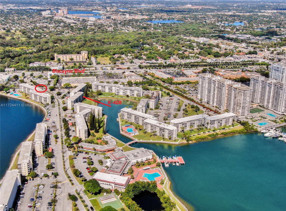 Aerial view of a residential area with several multi-story apartment buildings, parking areas, and surrounding waterways.