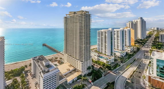 Panoramic view of high-rise buildings near the ocean with a pier extending into the water.