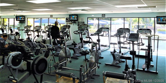 Indoor gym area with exercise equipment and large windows.