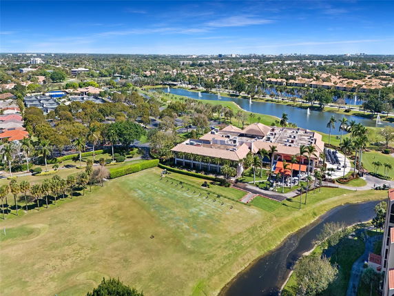 Aerial view of a large complex with multiple buildings surrounded by greenery, water features, and residential areas.