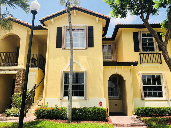 Front view of a two-story house with yellow exterior and black shutters.