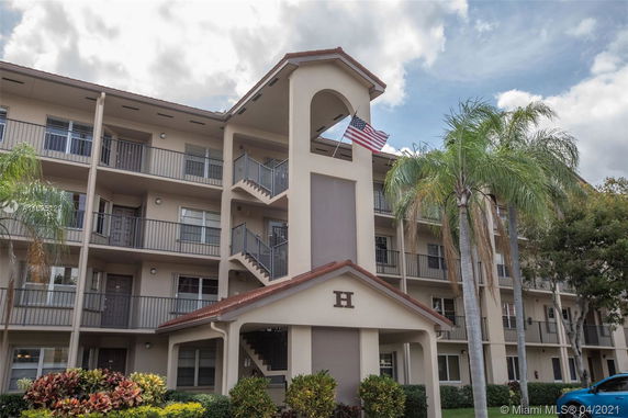 Front view of a multi-story apartment building with external staircases and a small archway.