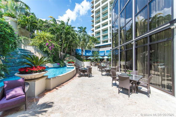 Outdoor seating area beside a pool and high-rise building.