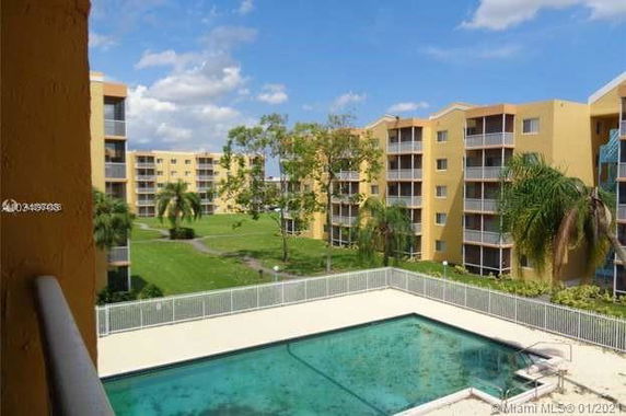View of apartment buildings with balconies surrounding a swimming pool.