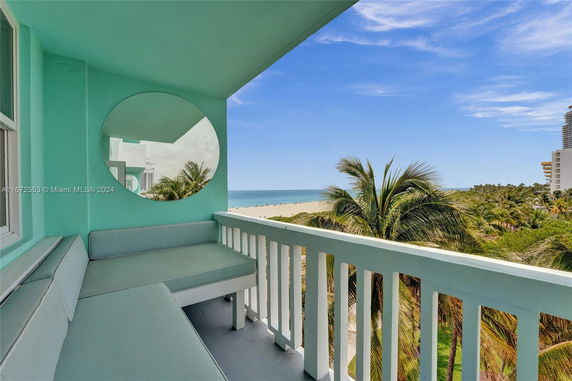 Balcony with seating area overlooking the beach and ocean.