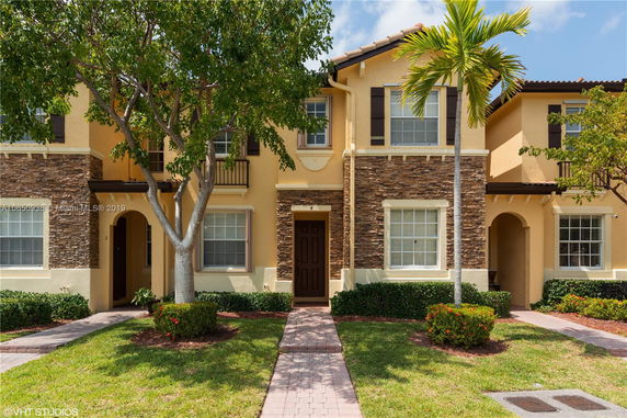 Front view of a two-story townhouse with a stone facade and arched entrance.