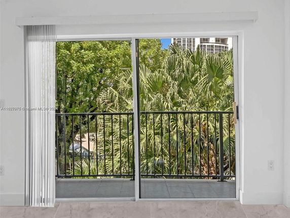View of greenery and surrounding buildings seen from a sliding glass door.