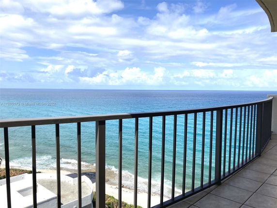 View of the ocean from a balcony with a metal railing.