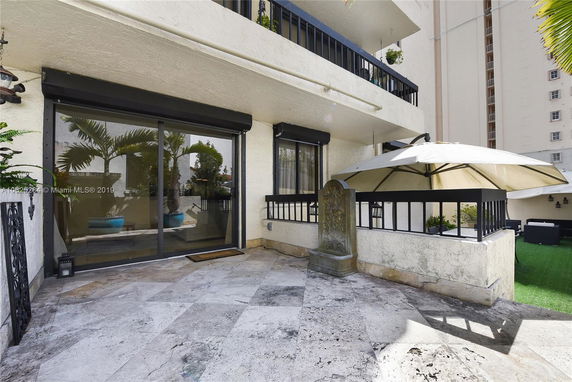 Outdoor patio area with sliding glass doors leading inside, an umbrella, and decorative elements.
