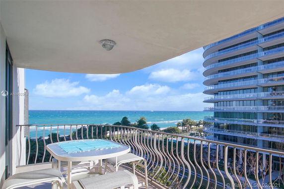 Balcony view overlooking the ocean and nearby buildings.